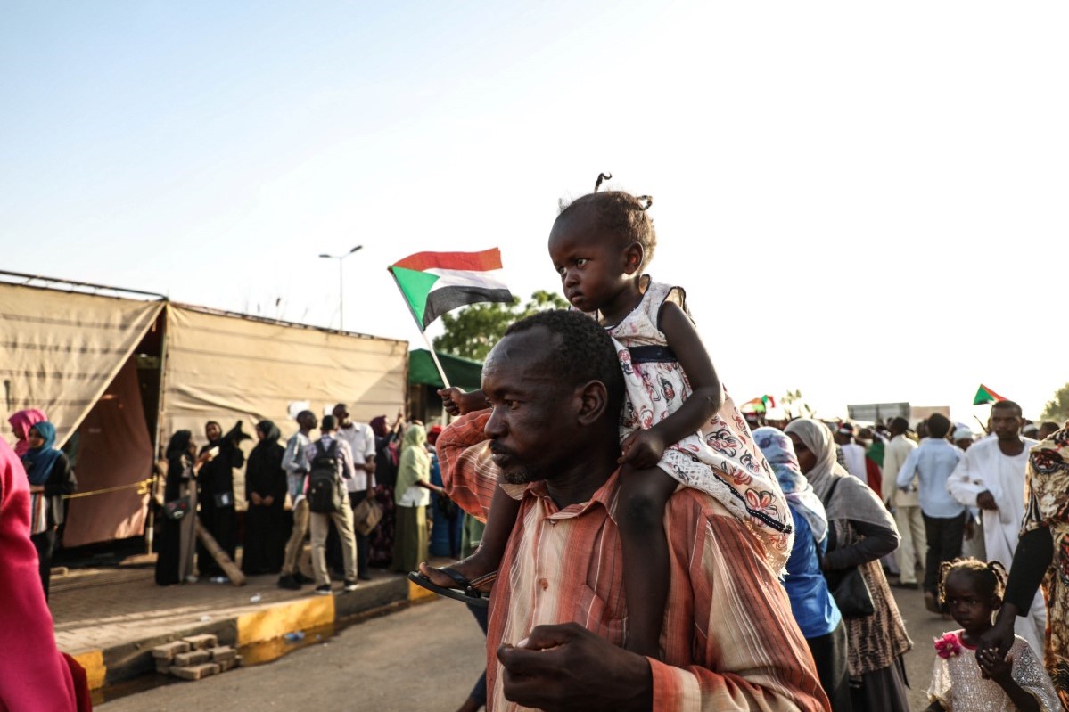 En mann med datter sittende på ryggen deltar i demonstrasjon i Khartoum, Sudan, 21. april 2019