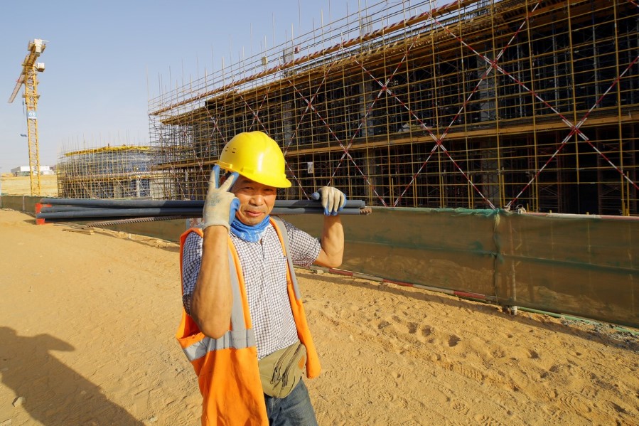 Kinesisk bygningsarbeider i den egyptiske ørkenen bærer armeringsjern og gir v-tegn
