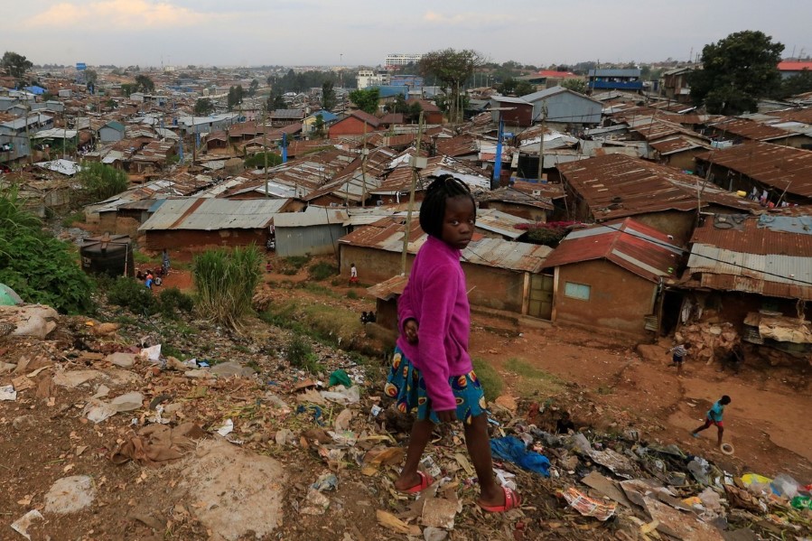 Ei jente står foran slummen i bydelen Kibera i Nairobi.
