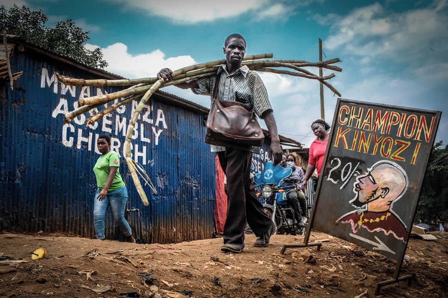 Copyright (c) 2020 Shutterstock. No use without permission.  11, A, PASSES, DAILY, SUGARCANES, POST, NAIROBI, BARBER, 2020, KIBERA, SHOP, AUG, SLUMS, BY, CARRYING, 90051997, MAN, SIGN, KENYA, LIFE